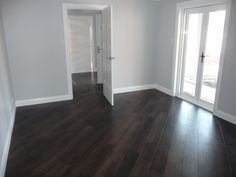 an empty room with hard wood floors and white trim on the doors, windows, and sliding glass doors