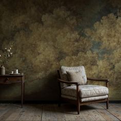 a chair and table in front of a wall with clouds painted on the wall behind it