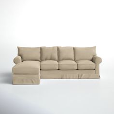 a beige couch with pillows on it and a footstool in front of it