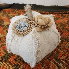 a decorative white pumpkin sitting on top of a colorful carpeted flooring covered in burlap