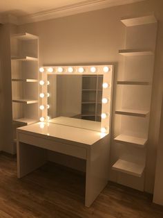 a white vanity with lights on it and shelves in front of the mirror that is lit up