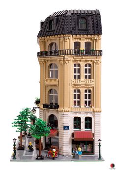 a large building made out of legos with people on the sidewalk and trees in front of it