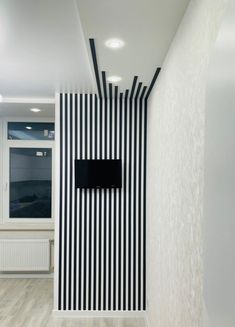 a black and white striped wall with a tv mounted to it's side in an empty room