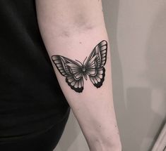 a black and white butterfly tattoo on the arm