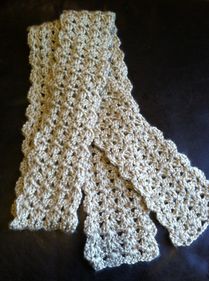 two crocheted scarfs laying on top of a black cloth covered in white yarn