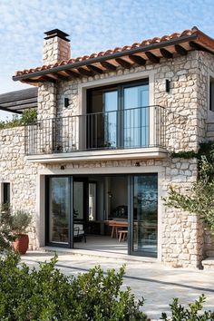 a stone house with glass doors and balcony