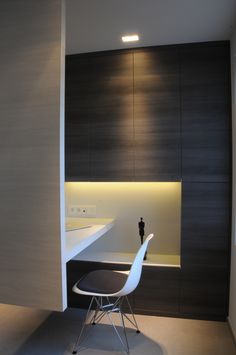 a white chair sitting in front of a desk next to a wall mounted sink and mirror