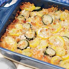 a person holding a blue casserole dish with zucchini and squash in it