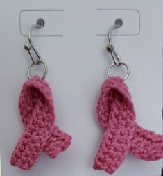 two pink crocheted bows hang from hooks on a white carded display holder