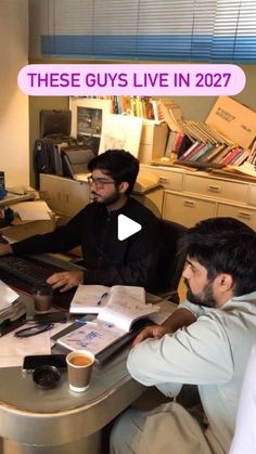 three men sitting at a desk with papers and laptops on it, one man is looking at the computer screen