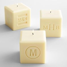 three square candles with the initials m & h and m on them, sitting next to each other