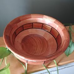 a wooden bowl sitting on top of a table next to a green leafy plant