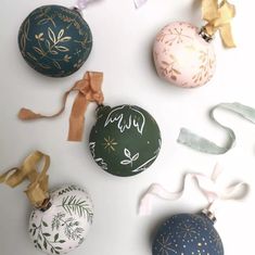 several ornaments are arranged on a white surface with ribbons and bows in the shape of an ornament