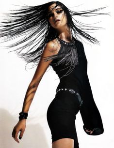 a woman with long black hair and tattoos on her arm is posing for the camera