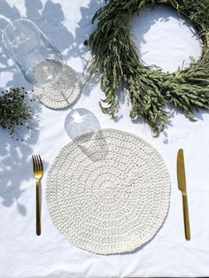 the table is set with silverware and greenery