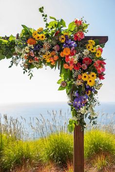 a cross decorated with colorful flowers and greenery