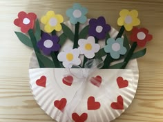 a paper plate with flowers and hearts on it sitting on top of a wooden table