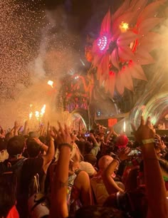 a large group of people at a concert with fireworks in the air and confetti being thrown into the air