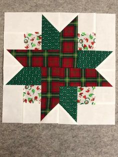 a green and red quilted star on top of a white table cloth next to a gray floor