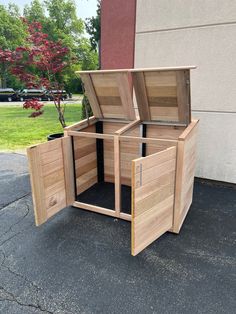 an open wooden box sitting on the ground next to a building with trees in it