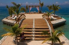 a wooden dock with lounge chairs and palm trees