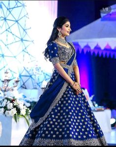 a woman in a blue and white bridal gown standing on the runway at an event