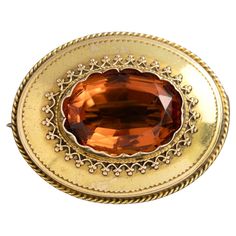 One Victorian yellow gold brooch featuring a central oval cut rich orange citrine quartz surrounded by fine wire work and engraving. Secured with a metal pin and hook catch. Due to the age and wear of this antique piece, there is evidence of a previous lead solder repair on the hinge of the brooch. Gemstone: One oval madeira citrine, estimated weight 11.30ct Metal: 15k yellow gold Weight: 7.60 grams Measurements: Length 4.0cm, width 2.5cm Era: Victorian Circa 1880s The Victorian era was one of romance. Queen Victoria was madly in love with her Albert, and the jewellery swayed in style accordingly. Orange Citrine, Gold Brooch, Gold Brooches, Metal Pins, Queen Victoria, Wire Work, Victorian Era, Oval Cut, Citrine