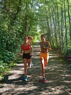 two women running down a trail in the woods