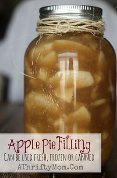 a jar filled with apples sitting on top of a wooden table next to a sign that says apple pie filling