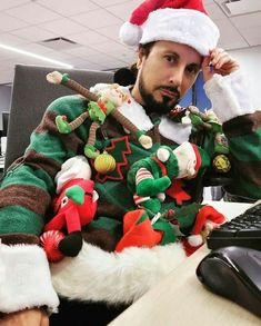 a man dressed in christmas sweaters sitting at a desk