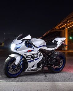 a white and blue motorcycle parked in front of a building at night with its lights on