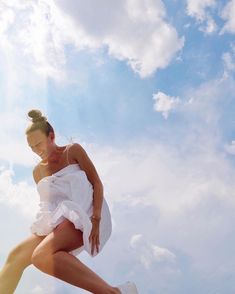 a woman in a white dress is flying through the air with her legs spread out