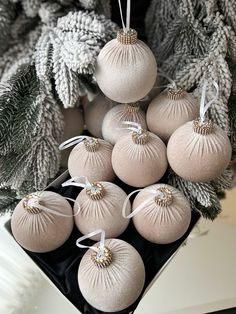 a bunch of ornaments hanging from a christmas tree in front of some pine cones and branches