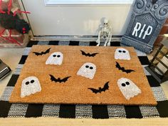 a halloween door mat with ghost faces and bats on it