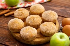 some sugary muffins and an apple on a wooden plate with cinnamon sticks