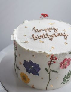 a birthday cake with flowers on it sitting on a white plate and the words happy birthday written in frosting