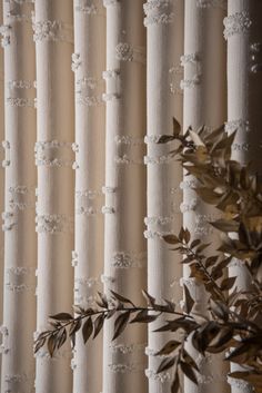 a close up view of a curtain with white beads and green leaves on the side