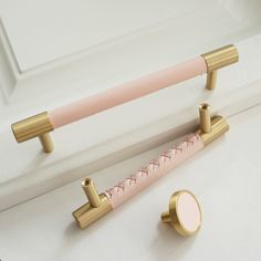 two pink and gold colored handles on a white door with a mirror in the background