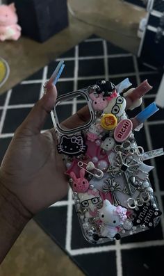 a person holding up a cell phone case with many different items attached to the back