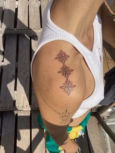 a woman with a tattoo on her back standing next to a wooden dock and looking down at the ground