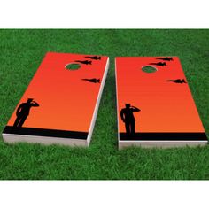 an orange and black cornhole board with two silhouettes on it in the grass