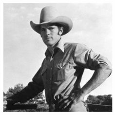 black and white photograph of a man wearing a cowboy hat with his hands on his hips