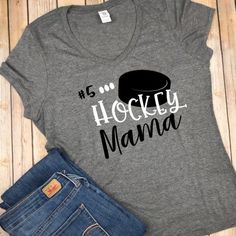 a shirt that says hockey mama with a top hat on it and some jeans next to it