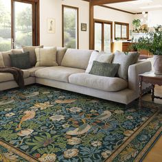 a living room with a large sectional couch and rug on the floor in front of windows