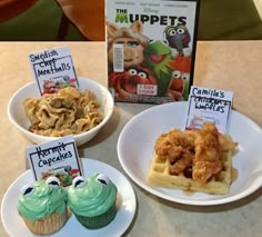 some kind of waffles and cupcakes on plates next to a box of muppets