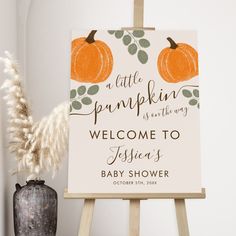 a little pumpkin is in the way welcome sign next to a potted plant and an easel