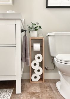 a bathroom with a toilet, sink and some rolls of toilet paper on the shelf