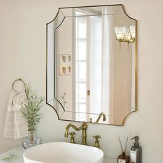 a bathroom sink sitting under a mirror next to a white counter top with gold faucet