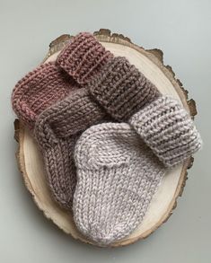 three knitted mittens sitting on top of a tree stump