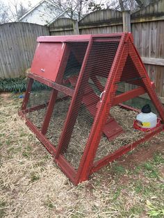 a red chicken coop in the yard with hay and other things around it on the ground